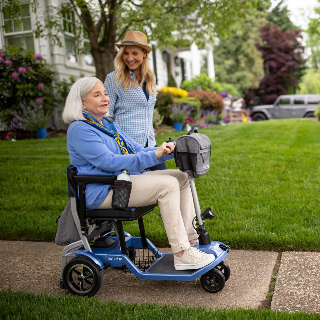 A rider on a Journey Health So Lite folding mobility scooter on a sidewalk