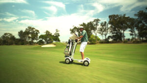 Side view of a person riding a Golf Skate Caddy swiftly across a golf course