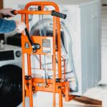 User turning the hand crank winch of the SuperHandy GUO097 to raise a dryer in a laundry room